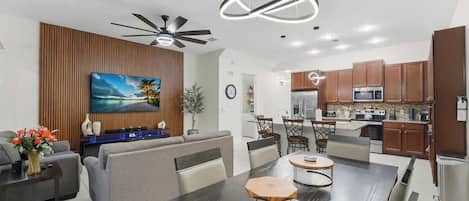 Una sala de estar moderna con comedor, cocina y ventilador de techo.