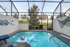 An indoor swimming pool with clear glass walls, a dolphin float, and a poolside lounge area. - Tranquil Times Townhouse 4 bed Private Pool (Davenport)