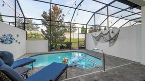 An indoor swimming pool with clear glass walls, lounge chairs, and a view of the outdoors. - Tranquil Times Townhouse 4 bed Private Pool (Davenport)