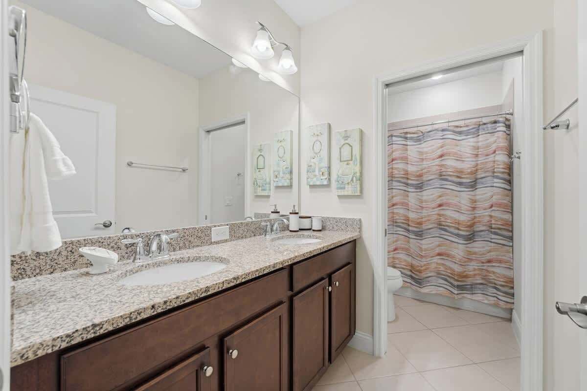 A bathroom with a double sink vanity, a large mirror, and a shower curtain.