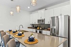 A modern kitchen with white cabinets, stainless steel appliances, and a central island with seating. - 4bd w Pool Amazing Free Resort (Davenport)