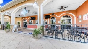 An outdoor patio area with a covered seating area, potted plants, and a clear sky. - Regal Palms 4bd Resort Tiki Bar (Davenport)