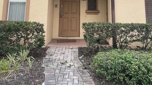 A two-story building with a beige facade, a central entrance with a brown door, and a small window above the door. - Regal Palms 4bd Resort Tiki Bar (Davenport)