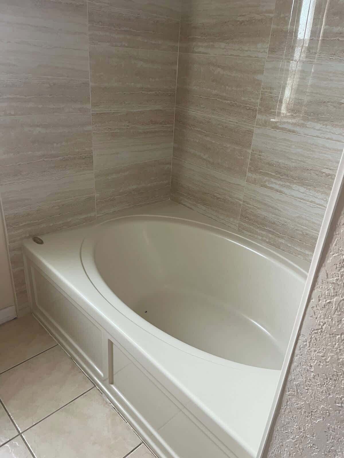 Un baño con bañera independiente, paredes y piso cubiertos de azulejos.