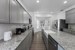 A modern kitchen with granite countertops, stainless steel appliances, and a central island. - Make Memories in This 6 Bedroom With Private Pool (Davenport)