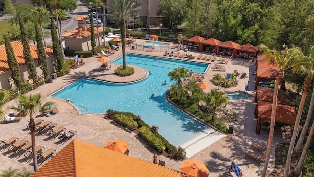 Een resort met een centraal zwembad, loungegedeeltes en meerdere gebouwen met rode pannendaken.