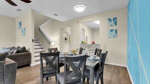 A modern living room with a staircase, dining area, and a blue accent wall. - Cute 3bd 2 5bth Amazing Resort (Davenport)