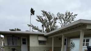 A single-story house with a covered porch, a front yard with a stone pathway, and a small garden area. - The Sandcastle-walk to the Beach and John s Pass (Madeira Beach)