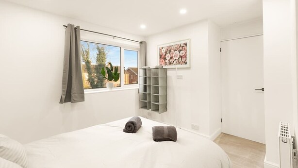 A modern bedroom with a large bed, a window with curtains, a radiator, and a wall-mounted shelf. - 3bed House - Close to Worksop Mansfield (Mansfield)