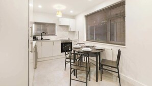 A compact kitchen with white cabinets, a built-in oven, a sink, and a dining area with a table and chairs. - 3bed House - Close to Worksop Mansfield (Mansfield)