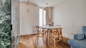 A dining area with a round table and four chairs, a blue sofa, and a window with curtains. - w Dreamy 1BR w Private Terrace Skyline View (Milan)