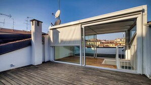 A rooftop terrace with a wooden deck, a sliding glass door, and a satellite dish. - w Dreamy 1BR w Private Terrace Skyline View (Milan)