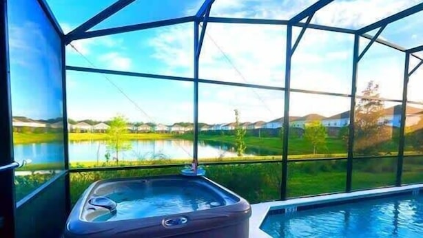 Un jacuzzi en un área acristalada con vistas a un lago y colinas.