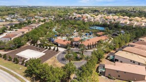 An aerial view of a residential area with houses, a central building with a swimming pool, and a landscaped area with palm trees. - Beautiful 6br5bathpool Clubhouse (Davenport)