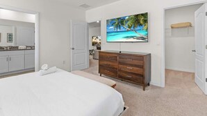 A bedroom with a large bed, a wooden dresser, a TV on the wall, and a closet. - Beautiful 6br5bathpool Clubhouse (Davenport)