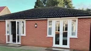 A single-story brick house with a tiled roof, white-framed windows, and a door with glass panels. - 1-bed Hideout in Ripon With Free Parking (Ripon)