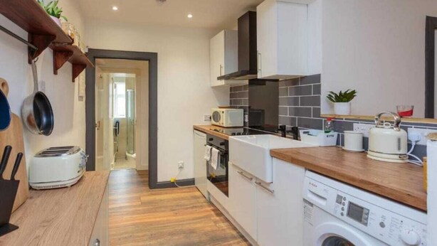 A compact kitchen with a microwave, toaster, oven, and washing machine. - 1 Bedroom Scottish Cottage-on Street Parking (Selkirk)