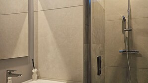 A modern bathroom with a glass-enclosed shower, a white sink, and a large mirror. - Love Room Le Jardin D'Éden (La Motte-Servolex)
