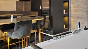 A modern bathroom with a large bathtub, a glass-enclosed shower, and a wooden door. - Love Room Le Jardin D'Éden (La Motte-Servolex)