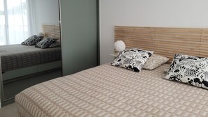 Ein Schlafzimmer mit einem Bett, einem Spiegel und einem Fenster.