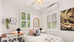 A bedroom with a bed, a desk, a chair, and two windows with shutters. - 1920s Cottage Near Paddington and CBD (Bardon)