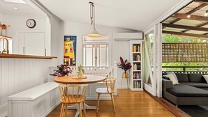 A modern kitchen with a wooden dining table, chairs, and a pendant light. - 1920s Cottage Near Paddington and CBD (Bardon)