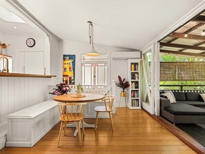 A modern kitchen with a wooden dining table, chairs, and a pendant light. - 1920s Cottage Near Paddington and CBD (Bardon)