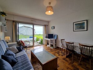 Ett modernt vardagsrum med soffa, soffbord, TV och matplats.