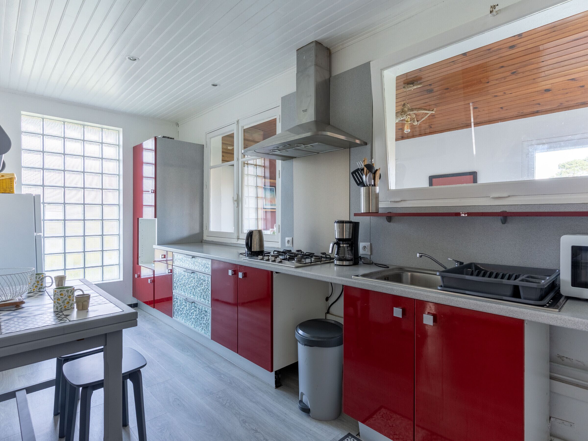 Una cucina moderna con mobili rossi, un lavello in acciaio inossidabile e un piano cottura a gas.