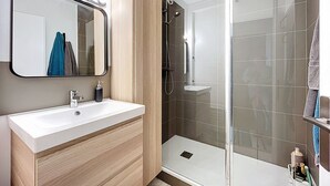 Un baño moderno con tocador, ducha con puerta de cristal y espejo con iluminación superior.