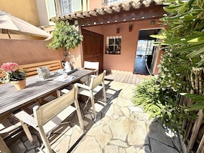 An outdoor patio with a wooden table and chairs, a potted plant, and a tiled floor. - Fisherman's House in Port Grimaud with Mooring and WiFi (Port Grimaud)