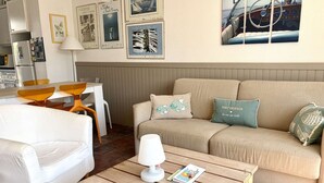 Ein Wohnzimmer mit einer Couch, einem Couchtisch, einer Lampe und einem gerahmten Bild eines Bootes.