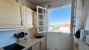 A compact kitchen with a window view, a sink, a stove, and cabinets. - 3-bedroom apartment with sea view, beach access, parking, in Port Grimaud (Port Grimaud)