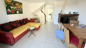 Ein Wohnzimmer mit einer Couch, einem kleinen Tisch, einem Fernseher und einem Kamin.