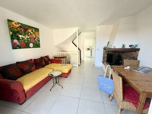 A living room with a sofa, a small table, a TV, and a fireplace. - Charming Duplex in Port Grimaud with Balconies and Parking (Port Grimaud)