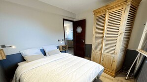 Une chambre à coucher avec un grand lit, une armoire en bois et un miroir.