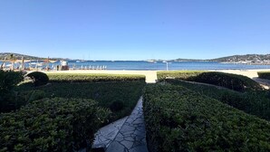 Ein Weg führt zu einem Strand mit Sonnenschirmen und freiem Blick auf das Meer.