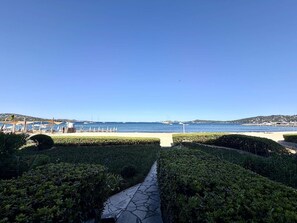 A pathway leading to a beach with umbrellas and a clear view of the sea. - 4-room apartment with balcony, sea view, wifi and parking (Port Grimaud)