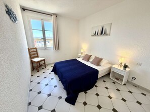A bedroom with a bed, a chair, a nightstand, a lamp, and a painting on the wall. - 4-room apartment with balcony, sea view, wifi and parking (Port Grimaud)