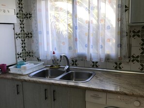 A kitchen with a double sink, a dish rack, and a dish soap bottle. - Seafront Apartment - Terrace & Air Conditioning (Miami Playa)