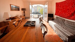 Een gezellige woonkamer met een houten eettafel, stoelen, een bank en een televisie.