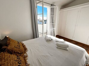 Une chambre à coucher avec un lit, une armoire et un balcon offrant une vue sur la ville.