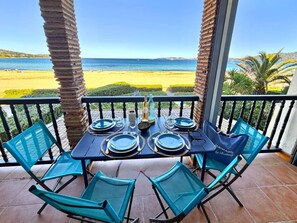 Mesa de comedor lista para cuatro personas, con vista a la playa y al océano.