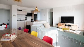 Eine moderne Wohnung mit Essbereich, Küche, Wohnzimmer und Fernseher.