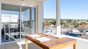 Ein Balkon mit einem Holztisch, zwei Stühlen und drei Weingläsern.