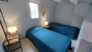 A bedroom with two beds, a nightstand, a lamp, a window, and a wall-mounted plant. - Air-conditioned pavilion for 6 pers. with parking & bikes in Gruissan (Gruissan)