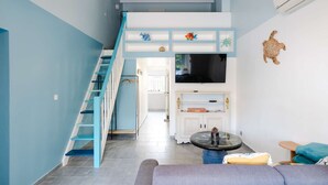 A modern living room with a blue staircase, a flat-screen TV, and a round coffee table. - Air-conditioned pavilion for 6 pers. with parking & bikes in Gruissan (Gruissan)