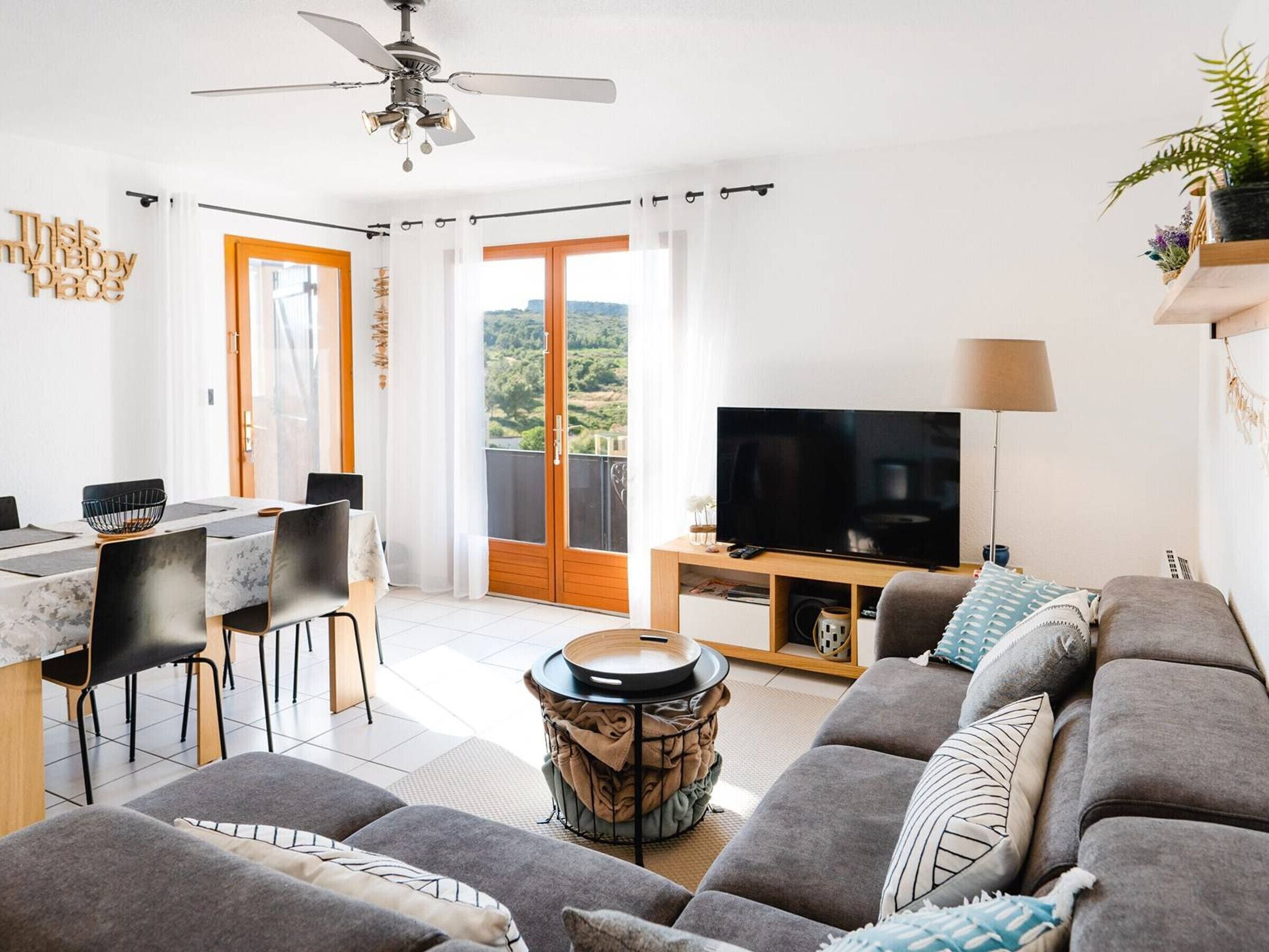 A modern living room with a sofa, TV, and dining area.