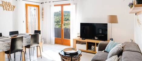 A modern living room with a sofa, TV, and dining area.