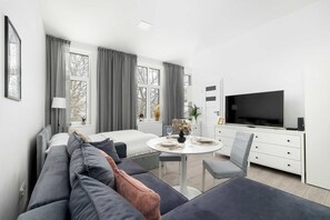 Une chambre d’hôtel moderne équipée d’un lit, d’un canapé, d’une table à manger et d’un téléviseur.